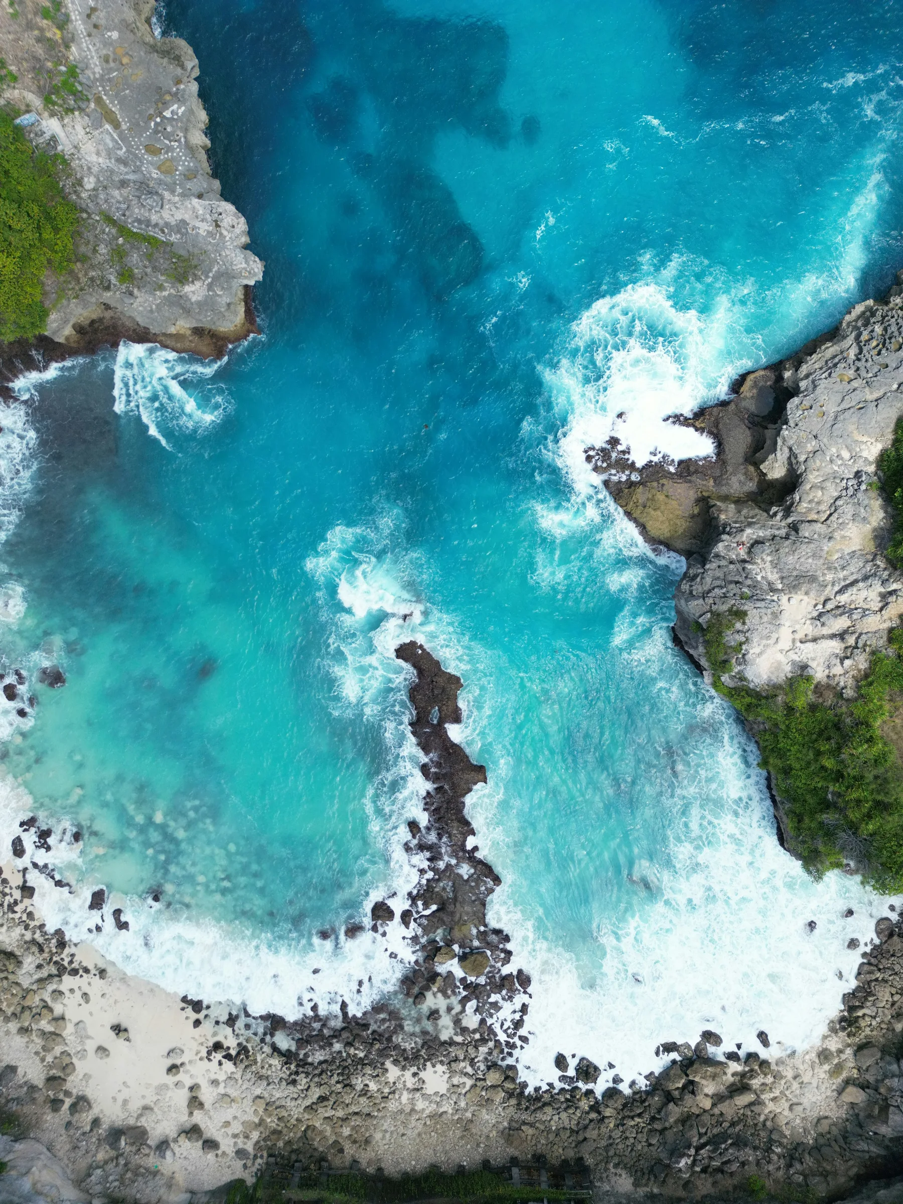 Turquoise waves breaking against the rocky coast at Blue Lagoon, Nusa Ceningan